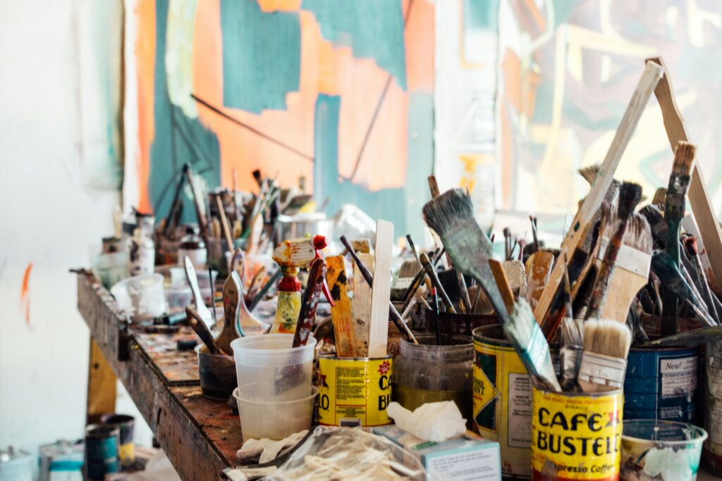 A wooden bench covered with buckets of paint brushes