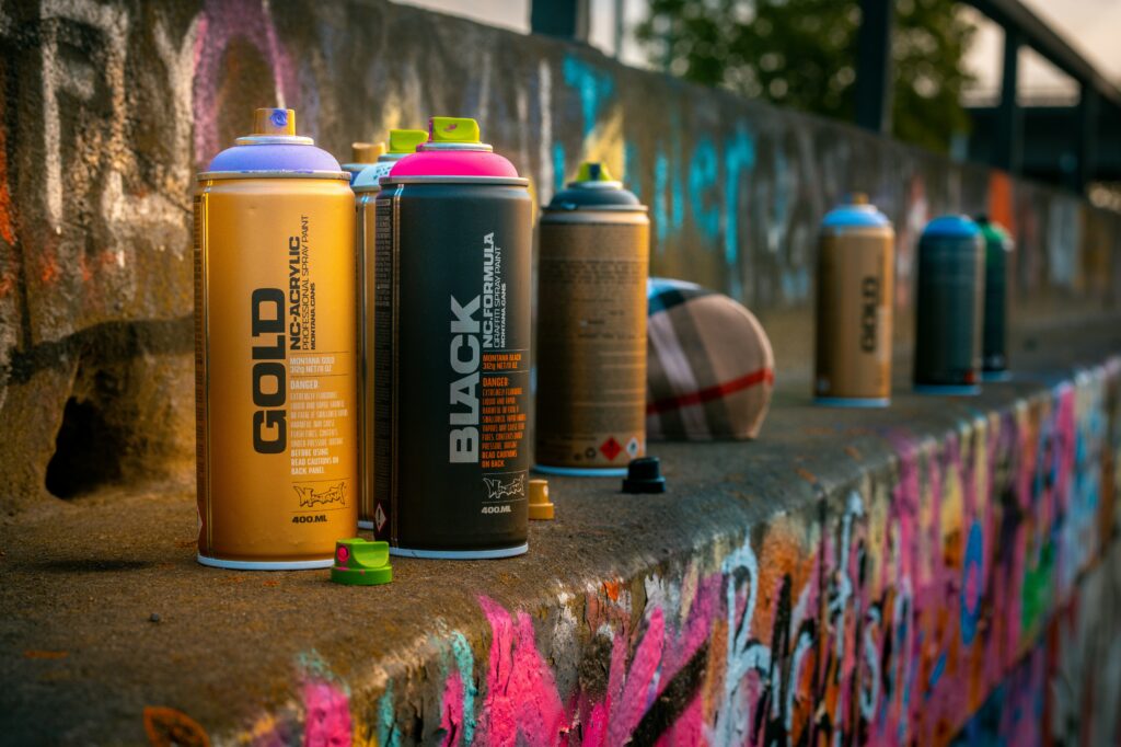A photograph of different colour spray cans sitting on a concrete wall