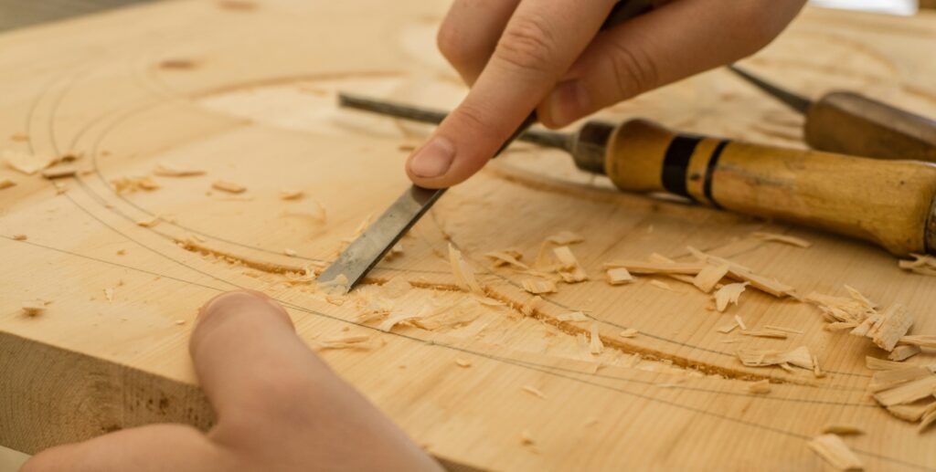 A photograph of an artisan carving a wooden sculpture