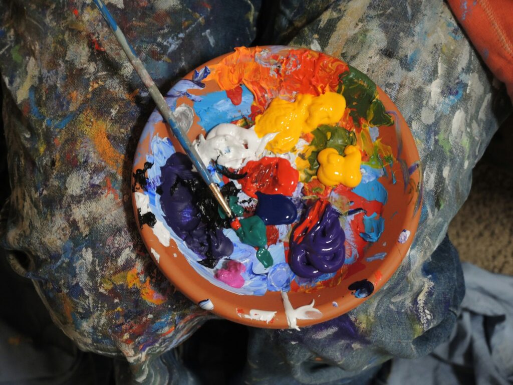 A photo of a terracotta bowl filled with different coloured paints