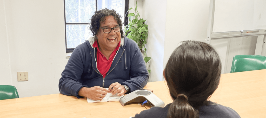 Photo of Aboriginal man smiling while talking to Arts Law representative in an office