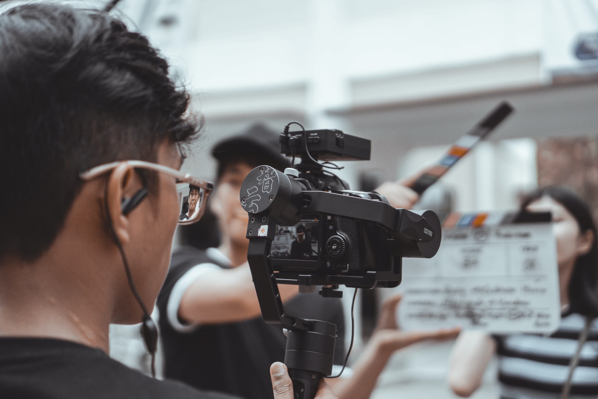 A man is stadning behind a video camera