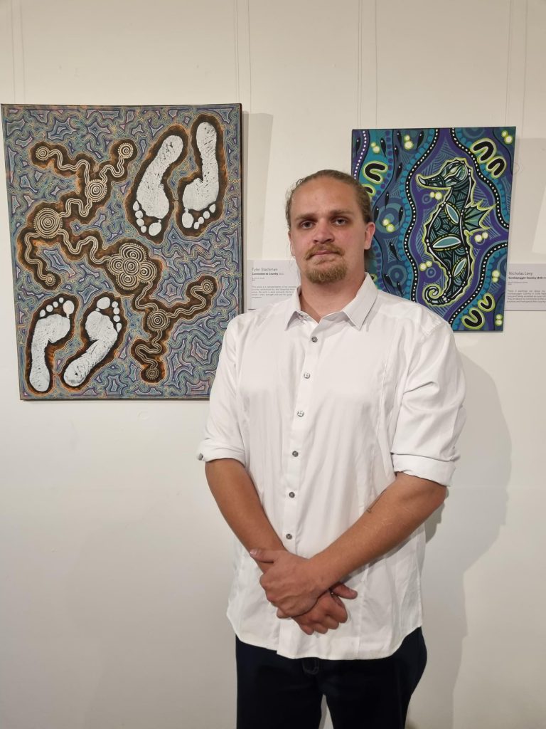Artist standing in front of their artworks